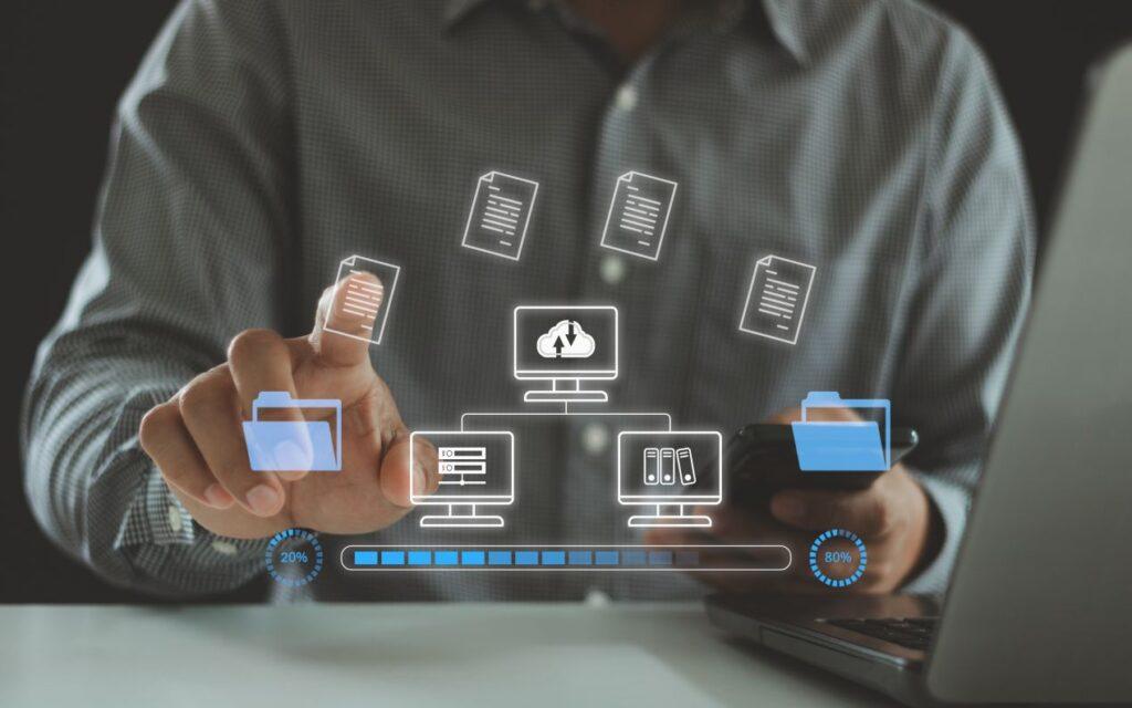 Mann nutzt Laptop und Smartphone mit virtueller Datenuebertragung – Symbolbild fuer digitale Netzwerke mit LWL Stecker